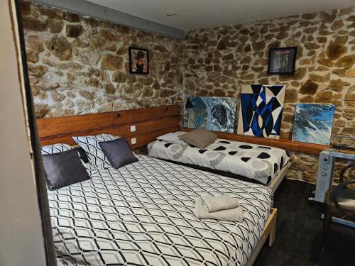 Dos camas en una habitación con pared de piedra. en Le Tempo, en Entrecasteaux