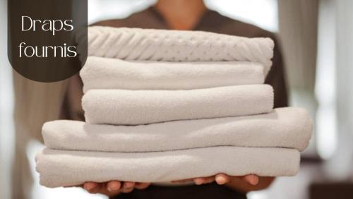 a person holding a stack of white towels at La Villa Tria Castella in Saint-Paul-Trois-Châteaux