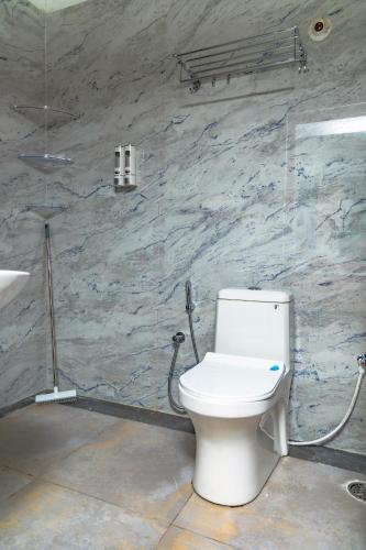 a bathroom with a white toilet and a sink at Aho Havens in Bangalore