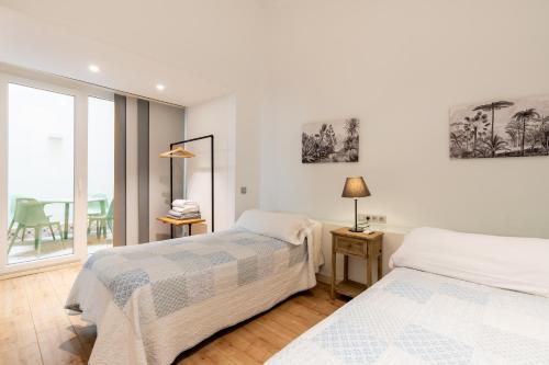 2 łóżka w białym pokoju z oknem w obiekcie Apartamentos Lanza w Sewilli