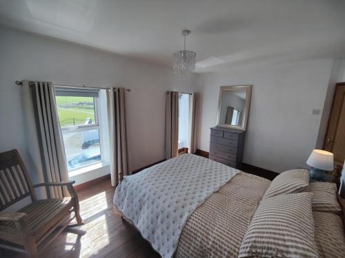 a bedroom with a bed and a chair and two windows at Rustic Pub Stay - 20 minutes from Killarney! in Rathmore