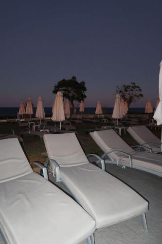 a row of lounge chairs and umbrellas on a beach at SUNNY COAST in Paralimni