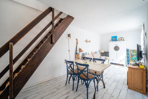 une salle à manger avec une table en bois et un escalier dans l'établissement L’Échappée Méditerranéenne - Proche Plage, à Leucate