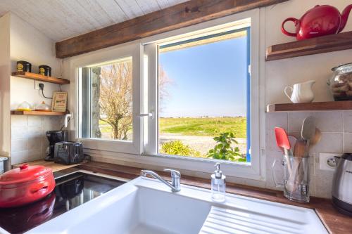 une cuisine avec un évier et une fenêtre dans l'établissement L’Échappée du Port - Grand Jardin, à Bouin