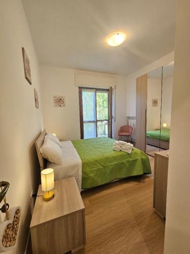 a bedroom with a large bed with a green blanket at Sara&Pietro's Home in Diano Marina