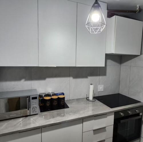 a kitchen with white cabinets and a microwave at Neat, instaworthy, self-checkin flat in Pretoria in Pretoria