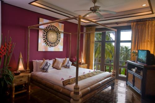 a bedroom with a canopy bed and a tv at Paradise Island Estate in Choeng Mon Beach