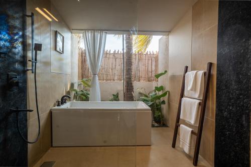 a bathroom with a white tub and a window at Kssemya in Mandrem