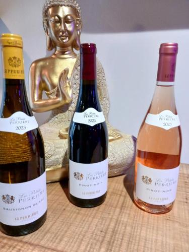 trois bouteilles de vin posées à côté d'une statue dans l'établissement le cocon de gepetto spa privatif, à Fussy