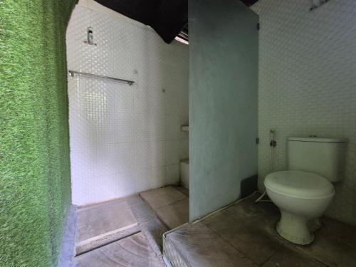 a bathroom with a toilet and a green wall at The Paica in Denpasar
