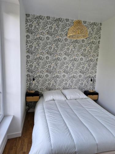 une chambre avec un lit blanc et un mur dans l'établissement Les Dunes Résidence face à la plage des Dunes, à Fouesnant