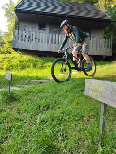 a man riding a bike in the grass near a sign at Slow Huts in Miedzygorze