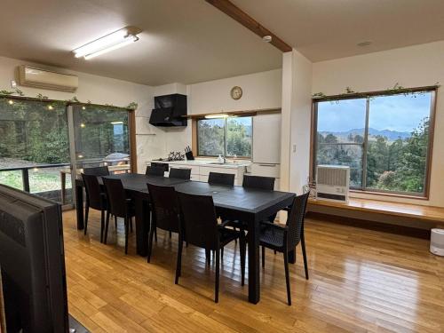 a kitchen and dining room with a black table and chairs at サウナパラダイス富山 in Minamiboso
