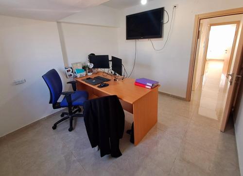 ein Büro mit einem Schreibtisch mit 2 Stühlen und einem TV in der Unterkunft דירה מרווחת ומוארת בבית שמש עם נוף מהמם! in Bet Schemesch