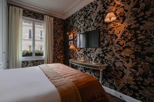 a bedroom with a bed and a tv on a wall at Hôtel De Buci in Paris