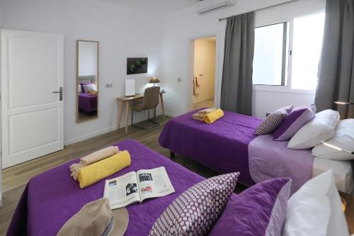 Pokój z dwoma fioletowymi łóżkami i stołem w obiekcie Luxury Puerto Calero Villa Casa Nublo 3 Bedrooms Private Pool Terrace With Seaviews Lanzarote w mieście Puerto Calero