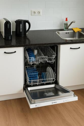 a dishwasher in a kitchen with dishes in it at Reza Almere in Almere