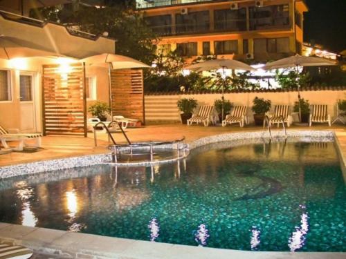 a swimming pool at night with chairs and umbrellas at Къща за гости Черно море in Sveti Vlas