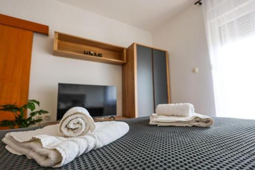 a bedroom with towels on a bed with a tv at Apartments Jasna in Crikvenica