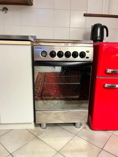 a stove in a kitchen next to a red refrigerator at Rifugio Rustico con Vista sulle Colline Toscane in Settignano