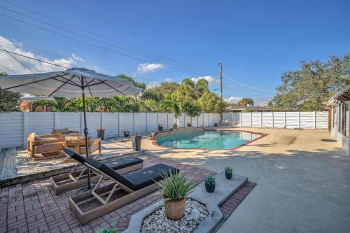 a patio with an umbrella and a swimming pool at Newly Renovated - Sunny Family Haven in Pompano in Pompano Beach