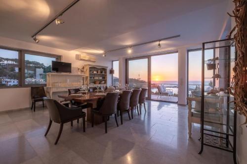 a dining room with a table and chairs and windows at Ikaria Beachfront Villa 7 Bedrooms Villa Indigo Blue Haven Infinity Pool With Stunning Aegian Sea Views Gialiskari in Gialiskari