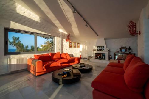a living room with orange furniture and a fireplace at Ikaria Beachfront Villa 7 Bedrooms Villa Indigo Blue Haven Infinity Pool With Stunning Aegian Sea Views Gialiskari in Gialiskari