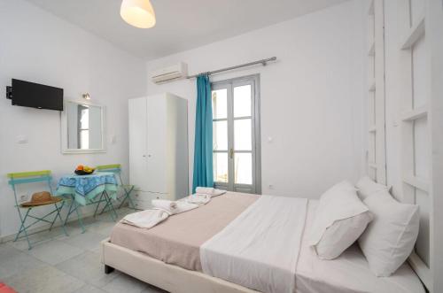 a white bedroom with a large bed and a table at Luxury Naxos Apartment Deluxe Triple Studio 150M From St George Beach City Center Saint George in Naxos Chora