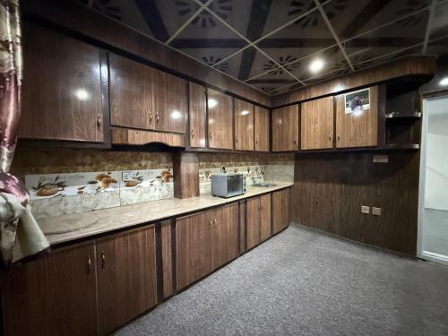 a kitchen with wooden cabinets and a microwave at Qasr اشرف in Skardu