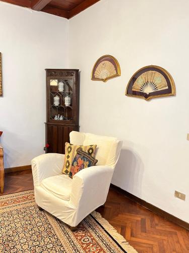 a living room with a white chair and a rug at Rifugio Rustico con Vista sulle Colline Toscane in Settignano