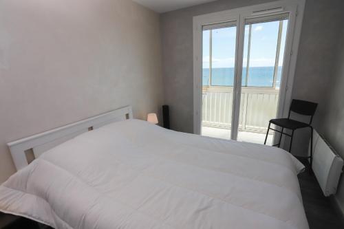 une chambre avec un lit blanc et une grande fenêtre dans l'établissement Moderne et lumineux appart face à la mer,, à Saint-Cyprien