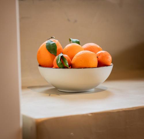 a bowl of oranges with green leaves on a table at Μάραθος in Kalavrita