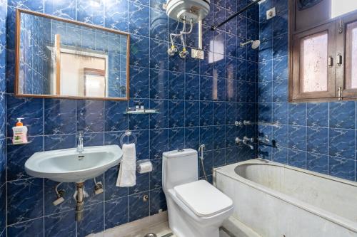 a blue tiled bathroom with a toilet and a sink at Homlee-Green Luxury 3BHK-South DEL-NFC-Fortis Hospital in New Delhi
