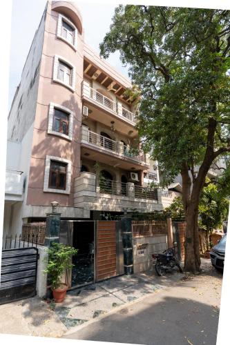 a tall pink building with a tree in front of it at Homlee-Green Luxury 3BHK-South DEL-NFC-Fortis Hospital in New Delhi