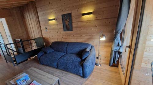 a living room with a blue couch and a wooden wall at Chalet Delphinette - Spa privatif in Morzine