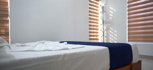 a white bed with a blue blanket on top of it at Smile Residency in Sultan Bathery