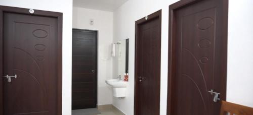 two brown doors in a bathroom with a toilet at Smile Residency in Sultan Bathery