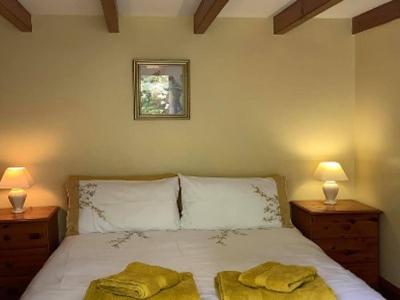 a bedroom with a bed with two yellow towels on it at Bwthyn Strathmore - Charming 18th-Century Cottage in Solva's Heart in Solva