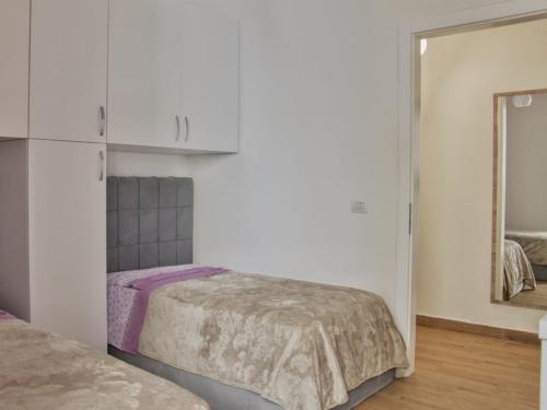 a white bedroom with a bed and a mirror at Deluxe Apartments Shengjin in Shëngjin