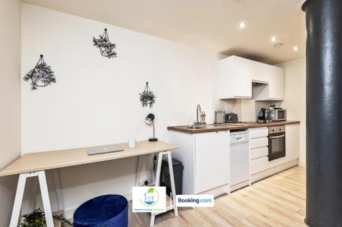 a kitchen with white cabinets and a wooden table at Spacious 1 Bedroom Apartment By Green Haven Escapes Short Lets & Serviced Accommodation Bradford With 4K Cinema Experience in Bradford