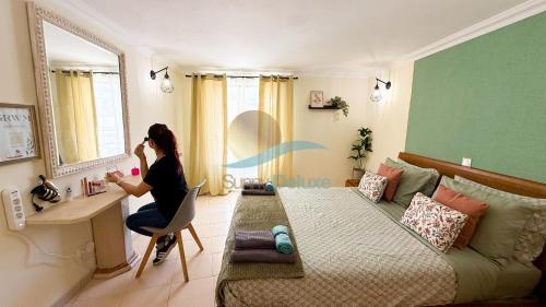 a woman sitting at a desk in a room with a bed at Villa Clara Premium by Sunny Deluxe in Albufeira
