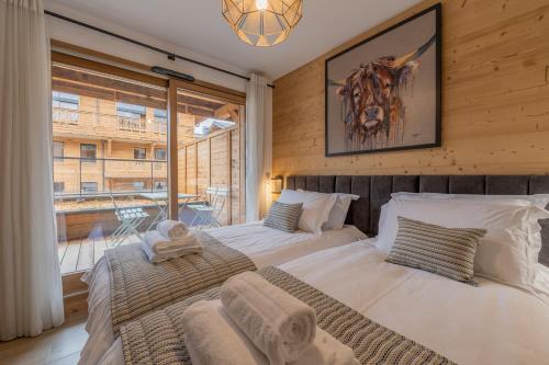 deux lits dans une chambre avec une grande fenêtre dans l'établissement Toluvie Apartment - Snow and Trek, à Morzine