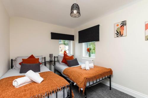 two twin beds in a room with two windows at Victoria Cottage Seaside - Spacious 4-BR in Bognor Regis,close to Beachfront & 2 minutes from Butlins Holiday Camp in Felpham