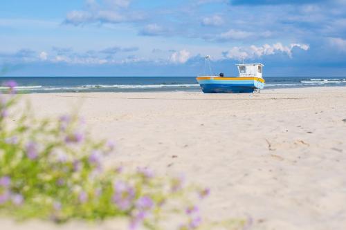 a boat sitting on the beach near the ocean at APARTAMENTY MIERZEJA - Apartament Zmysłów z prywatnym Jacuzzi tylko dla Dorosłych, 500 m od plaży, Stegna Park II, bezpłatny meleks in Stegna