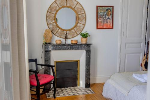 Cette chambre dispose d'une cheminée avec un miroir et une chaise. dans l'établissement L'Intemporel - By PrestiPlace, à Tours