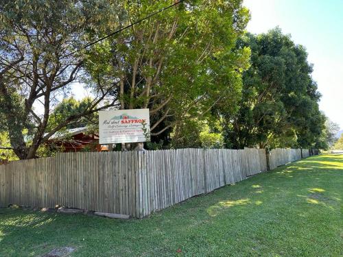 a fence with a sign in front of a yard at Mad About Saffron in Stormsrivier
