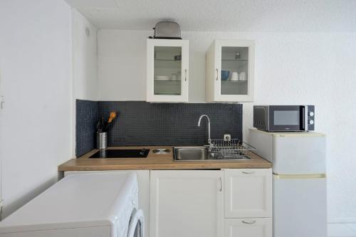 une cuisine avec des armoires blanches, un évier et un micro-ondes dans l'établissement Comfortable Studio Near The Old Port!, à Marseille