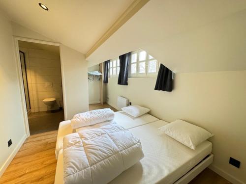 une chambre avec un lit avec des draps blancs et une fenêtre dans l'établissement Studio rénové dans une charmante résidence, à Saint-Étienne