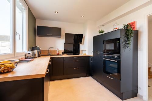 - une cuisine avec des appareils noirs et un comptoir en bois dans l'établissement Le Théodora - Balcon - Jardin - Parking, au Mans