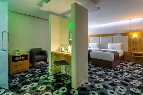 a hotel room with a bed and a desk and chair at Holiday Inn Sittingbourne by IHG in Sittingbourne